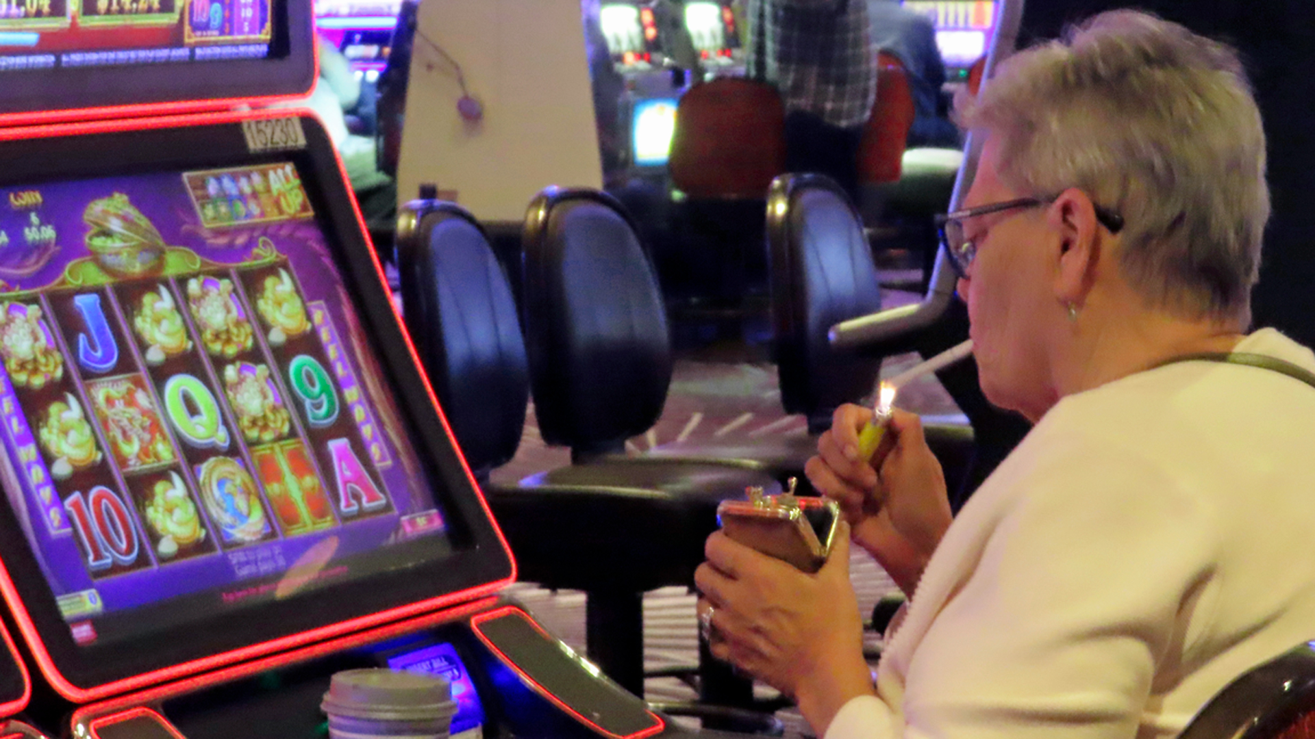 A woman smoking while playing a slot machine inside Magic City Casino